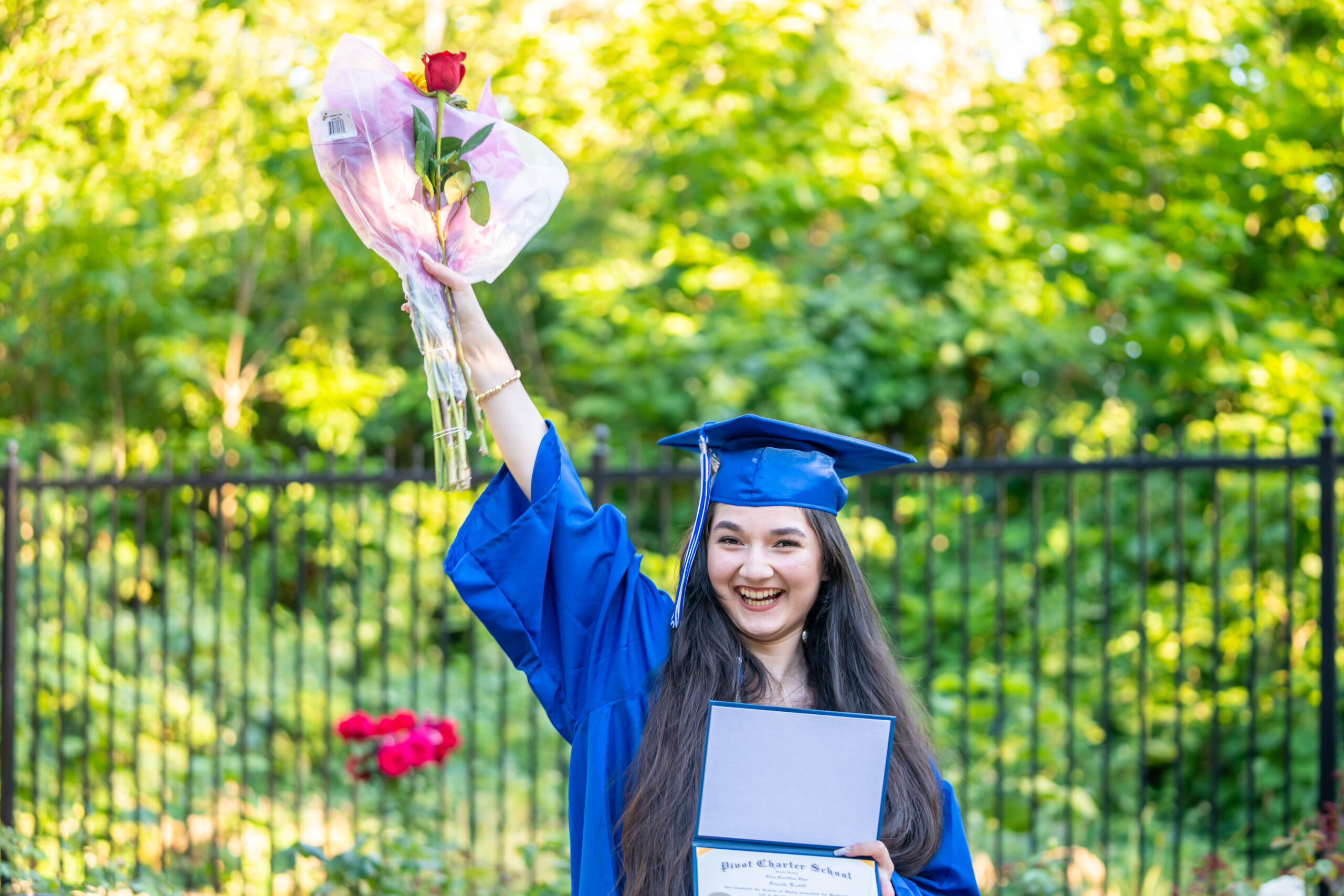 DSC09952 Graduate in cap and gown holding up a flower at her graduation ceremony